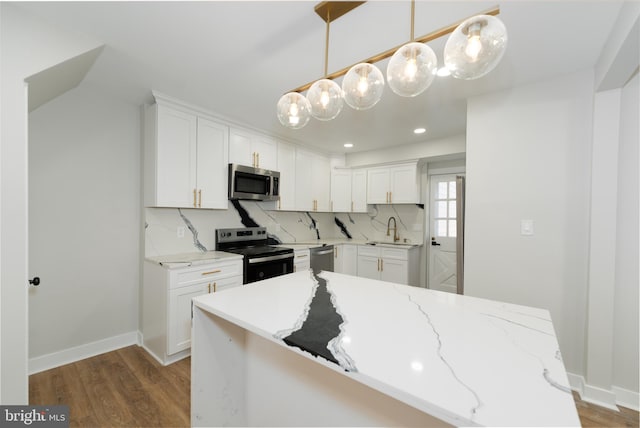 kitchen featuring appliances with stainless steel finishes, a sink, wood finished floors, white cabinetry, and recessed lighting