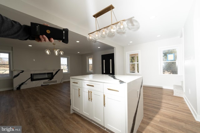 kitchen with white cabinets, wood finished floors, hanging light fixtures, baseboards, and recessed lighting