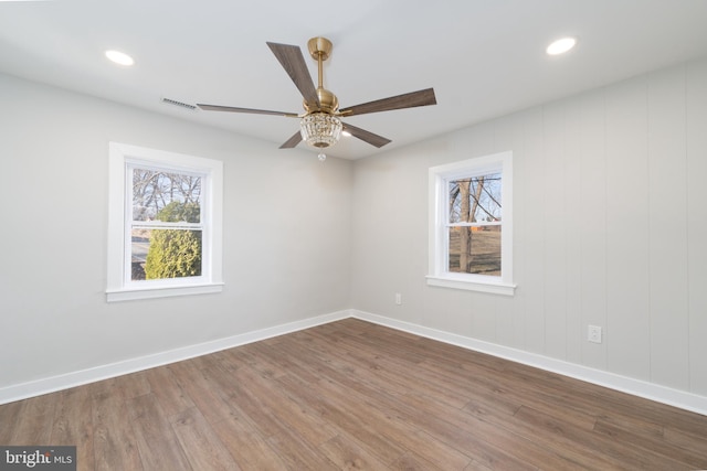 spare room with plenty of natural light, ceiling fan, wood finished floors, baseboards, and recessed lighting