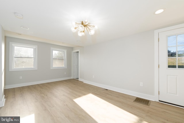 spare room with a chandelier, light wood-type flooring, baseboards, and a smoke detector