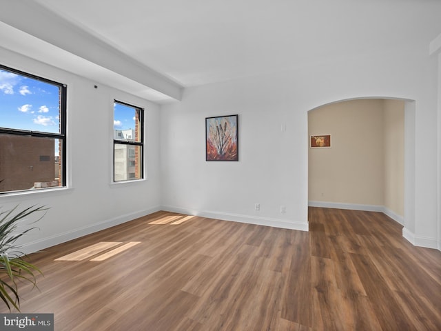 2515 K St NW Unit 807, Washington, DC 20037 - empty room featuring wood finished floors, arched walkways, and baseboards