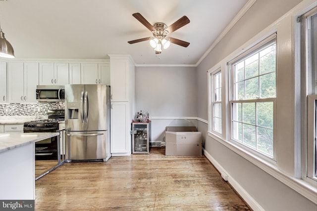 4208 Longfellow St, Hyattsville, MD 20781 - kitchen with appliances with stainless steel finishes, healthy amount of natural light, ornamental molding, white cabinets, and light wood finished floors