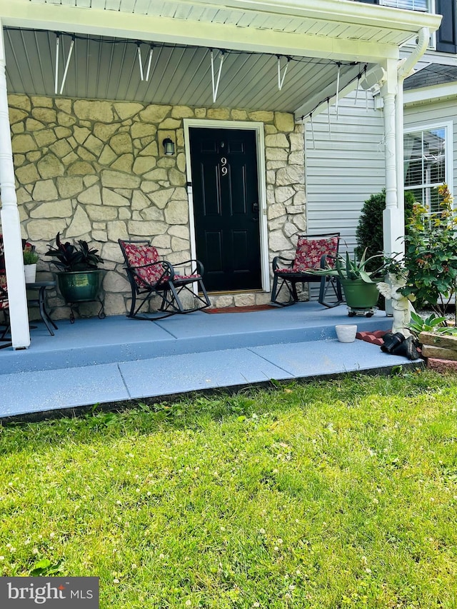99 Berkley Rd, Reading, PA 19605 - doorway to property featuring covered porch, stone siding, and a lawn
