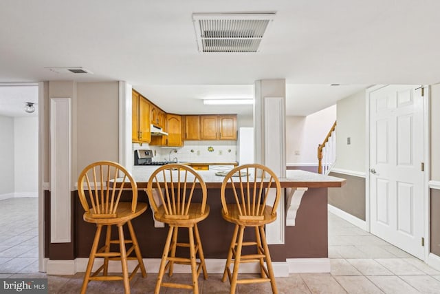 508 Weeks Ave, Riverside, NJ 08075 - kitchen with under cabinet range hood, range, light tile patterned floors, light countertops, and a peninsula
