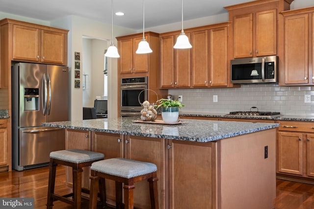 409 Pear Blossom Rd, Stafford, VA 22554 - kitchen with stainless steel appliances, dark wood finished floors, a kitchen island, a kitchen bar, and dark stone countertops