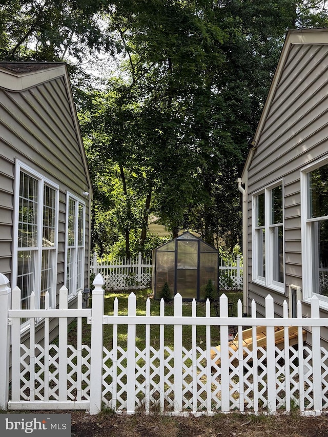 12534 Fawn Dr, Laurel, DE 19956 - fenced yard featuring a greenhouse, an outbuilding, and view of wooded area