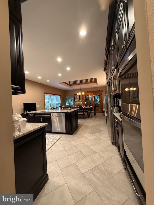 12534 Fawn Dr, Laurel, DE 19956 - kitchen featuring appliances with stainless steel finishes, dark cabinetry, light stone counters, recessed lighting, and a chandelier