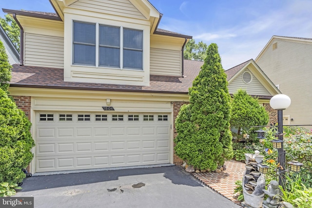 7504 Walnut Hill Ln, Falls Church, VA 22042 - traditional-style home with roof with shingles, brick siding, an attached garage, and driveway
