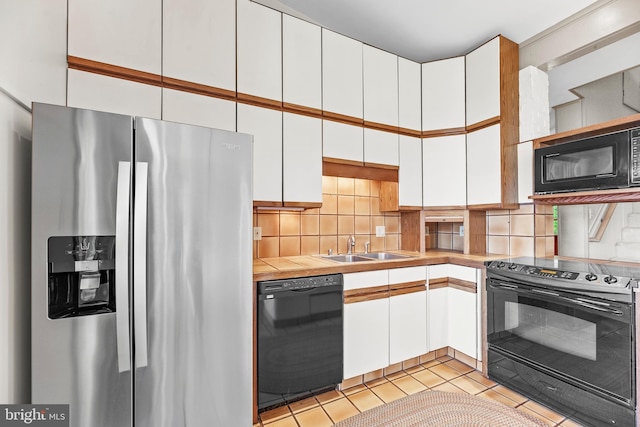 kitchen with black appliances, white cabinets, backsplash, and a sink