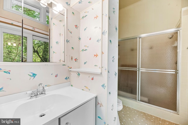 full bath with a shower with shower door, toilet, vanity, and tile patterned flooring