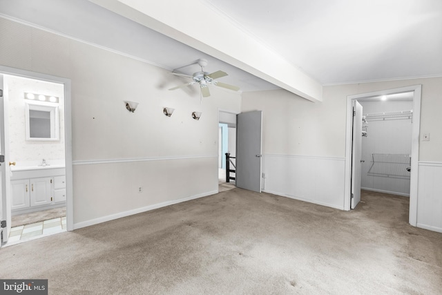 unfurnished bedroom featuring carpet floors, a walk in closet, crown molding, a closet, and ensuite bath