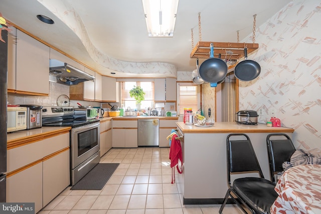 1200 Gainsboro Rd, Bala Cynwyd, PA 19004 - kitchen featuring stainless steel appliances, under cabinet range hood, light tile patterned flooring, light countertops, and wallpapered walls