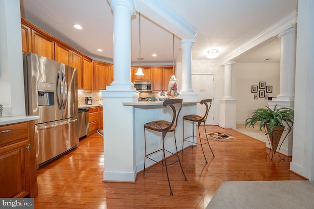 1322 Meridian Blvd Unit 1322, Warrington, PA 18976 - kitchen with stainless steel appliances, ornate columns, a kitchen breakfast bar, brown cabinetry, and crown molding