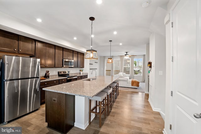 18216 Summit Pointe Dr, Triangle, VA 22172 - kitchen with appliances with stainless steel finishes, a sink, dark brown cabinets, light wood finished floors, and recessed lighting