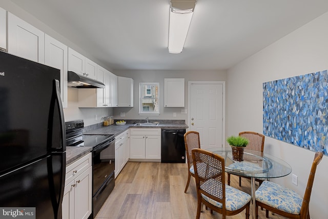 921 N Rose St, Baltimore, MD 21205 - kitchen with black appliances, under cabinet range hood, light wood finished floors, white cabinets, and dark countertops