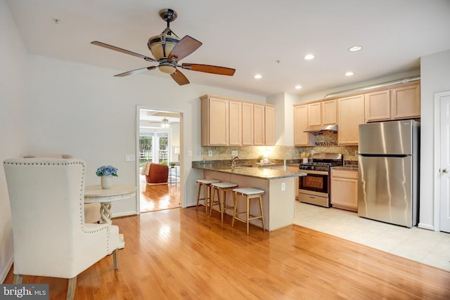 13943 Lullaby Rd, Germantown, MD 20874 - kitchen with appliances with stainless steel finishes, a peninsula, under cabinet range hood, ceiling fan, and decorative backsplash