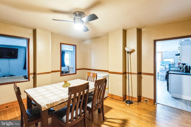 dining area featuring wood finished floors, a ceiling fan, and baseboards