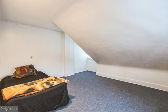 bedroom featuring lofted ceiling, dark colored carpet, and baseboards