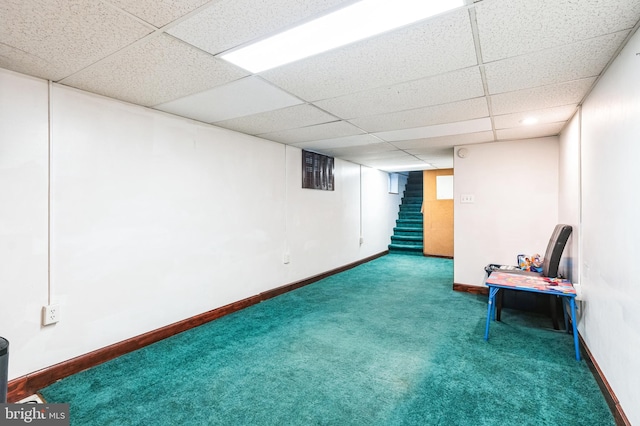 finished below grade area with stairway, a drop ceiling, carpet floors, and baseboards