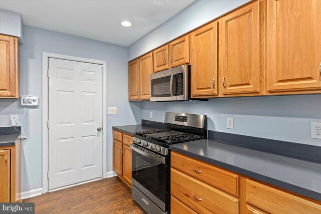 23115 Mt Cloud Rd, Bowling Green, VA 22427 - kitchen featuring appliances with stainless steel finishes, dark countertops, dark wood-style floors, baseboards, and brown cabinets