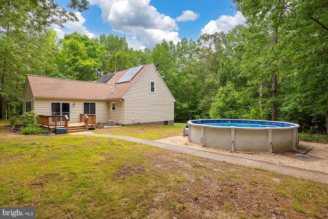 23115 Mt Cloud Rd, Bowling Green, VA 22427 - back of house with a wooden deck, an outdoor pool, roof mounted solar panels, a lawn, and a shingled roof