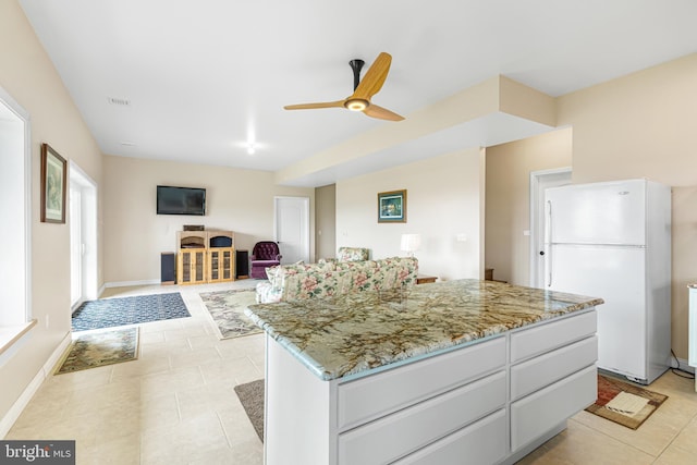 9207 Douglas Rd, Olanta, PA 16863 - kitchen with freestanding refrigerator, ceiling fan, light stone countertops, light tile patterned floors, and a center island