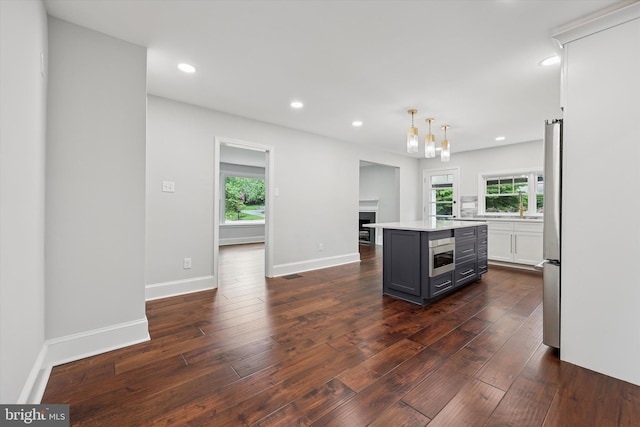 kitchen featuring appliances with stainless steel finishes, plenty of natural light, dark wood finished floors, light countertops, and recessed lighting