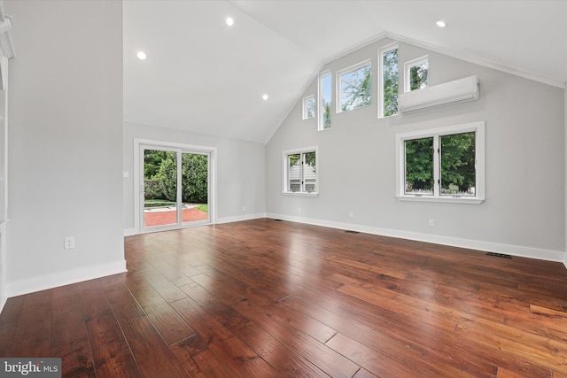 unfurnished living room with hardwood / wood-style flooring, a wall unit AC, high vaulted ceiling, baseboards, and recessed lighting