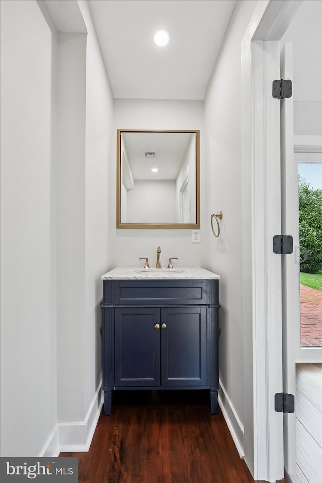 bathroom with baseboards, wood finished floors, and vanity