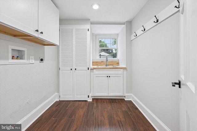 washroom featuring cabinet space, electric dryer hookup, dark wood-type flooring, washer hookup, and baseboards