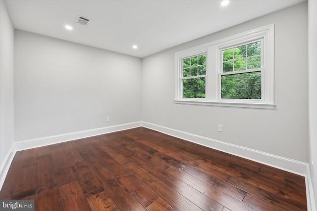 empty room with baseboards, dark wood-type flooring, and recessed lighting
