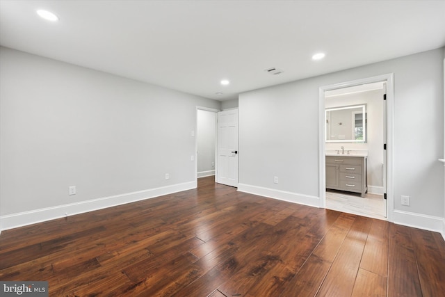 unfurnished bedroom with a sink, dark wood finished floors, baseboards, recessed lighting, and connected bathroom