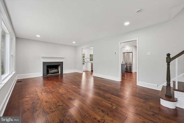unfurnished living room with stairway, dark wood-style floors, a fireplace with flush hearth, recessed lighting, and baseboards