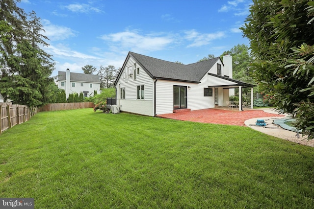 back of property with a patio area, a shingled roof, and a chimney