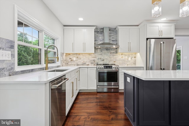 kitchen featuring wall chimney range hood, appliances with stainless steel finishes, a sink, light countertops, and recessed lighting