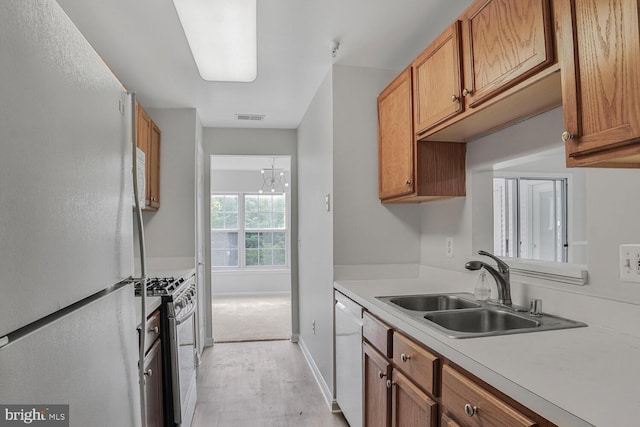 6510 Lake Park Dr Unit 2E/201, Greenbelt, MD 20770 - kitchen featuring white appliances, a sink, light countertops, brown cabinetry, and light wood finished floors