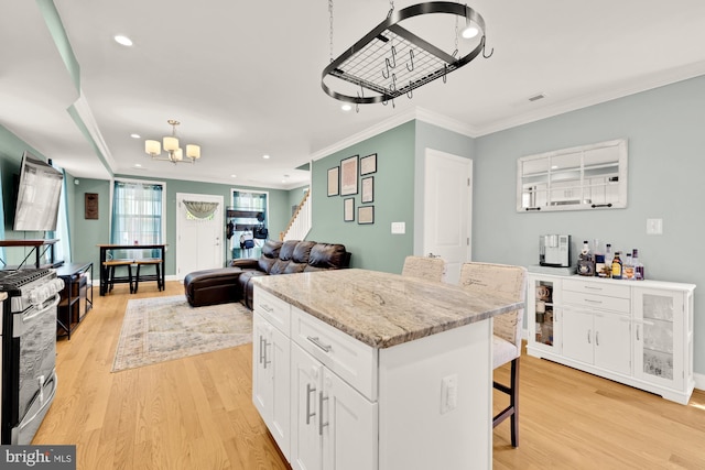 4521 Clay St NE, Washington, DC 20019 - kitchen featuring a chandelier, stainless steel range with gas stovetop, light wood-style floors, ornamental molding, and white cabinetry