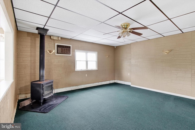 166 Tulpehocken St, Bernville, PA 19506 - unfurnished living room with a wood stove, carpet floors, a ceiling fan, a paneled ceiling, and a wall unit AC