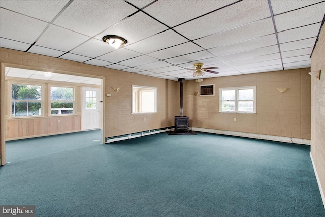 166 Tulpehocken St, Bernville, PA 19506 - carpeted empty room with a wood stove, a paneled ceiling, a baseboard heating unit, brick wall, and plenty of natural light