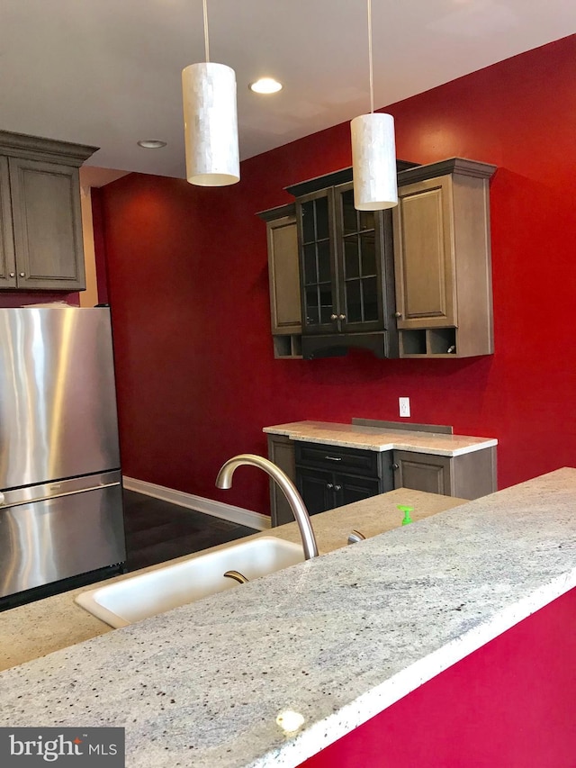 2205 E Baltimore St, Baltimore, MD 21231 - kitchen with freestanding refrigerator, a sink, light countertops, pendant lighting, and glass insert cabinets