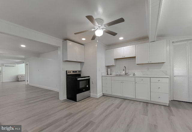 kitchen featuring stainless steel electric range, a sink, light countertops, light wood-style flooring, and white cabinetry