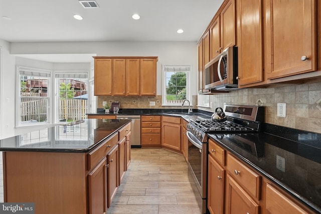8313 Middle Ruddings Dr, Lorton, VA 22079 - kitchen featuring stainless steel appliances, a sink, dark stone counters, light wood-style flooring, and backsplash