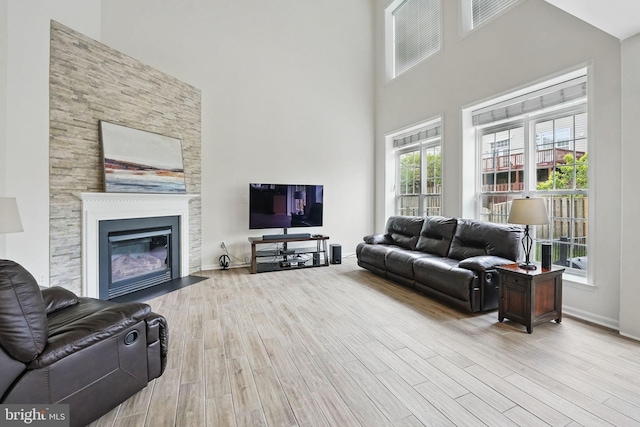 8313 Middle Ruddings Dr, Lorton, VA 22079 - living area with wood finished floors, a towering ceiling, a fireplace with flush hearth, and baseboards