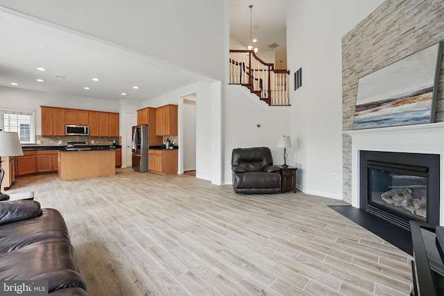 8313 Middle Ruddings Dr, Lorton, VA 22079 - living room featuring a towering ceiling, stairway, light wood finished floors, a large fireplace, and a chandelier