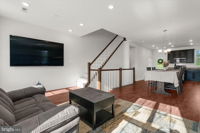 living area with wood finished floors, a chandelier, recessed lighting, stairway, and baseboards