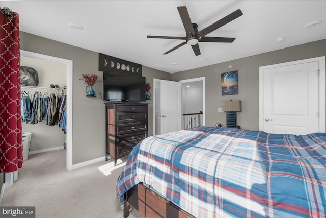 bedroom featuring baseboards, carpet floors, a walk in closet, a closet, and a ceiling fan