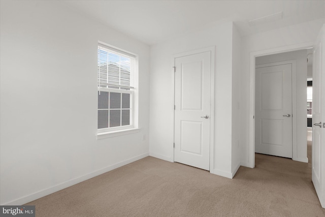 unfurnished bedroom featuring light carpet and baseboards
