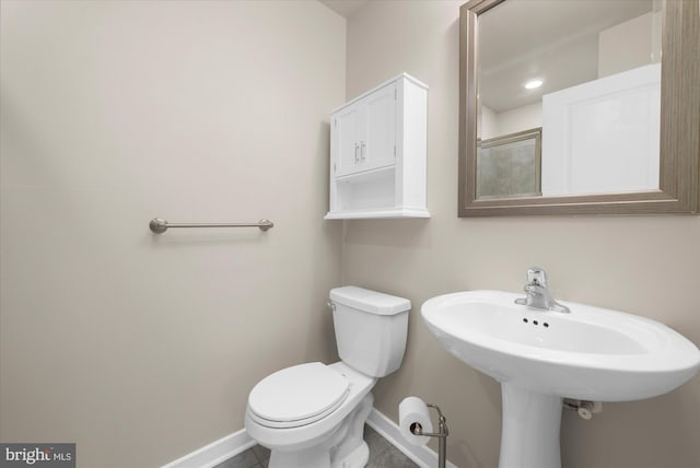 bathroom with baseboards, toilet, tile patterned flooring, and a sink
