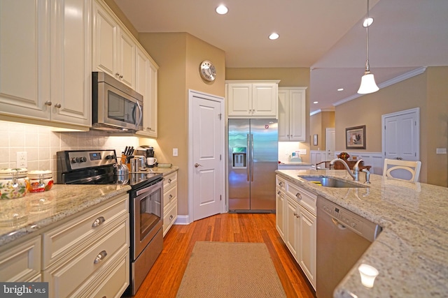 322 Captains Cir, Lewes, DE 19958 - kitchen with stainless steel appliances, a sink, light wood-type flooring, backsplash, and pendant lighting