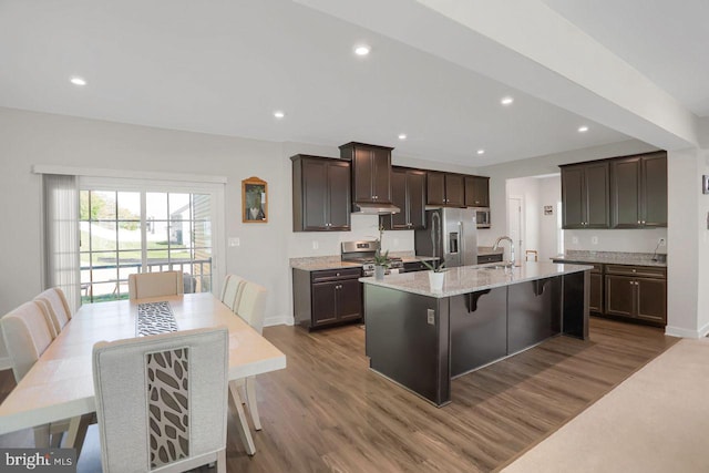 2005 Benjamin Ct, Harrisburg, PA 17110 - kitchen with appliances with stainless steel finishes, an island with sink, dark brown cabinets, wood finished floors, and a kitchen breakfast bar